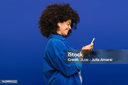 istock Carefree young woman playing music using a smartphone and earbuds 1429991322