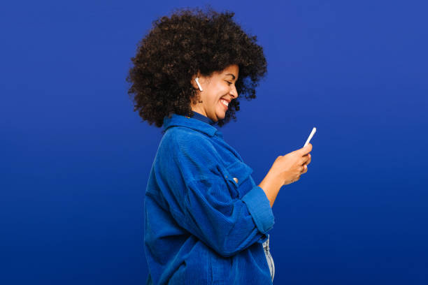 carefree young woman playing music using a smartphone and earbuds - telemovel imagens e fotografias de stock