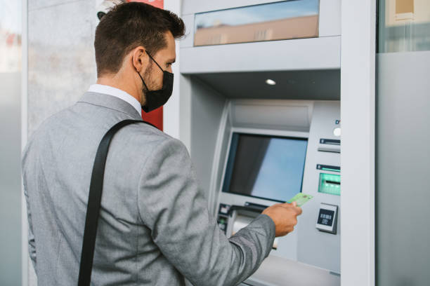 istock Businessman on city street using ATM machine 1429991368