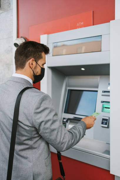 istock Businessman on city street using ATM machine 1429991371