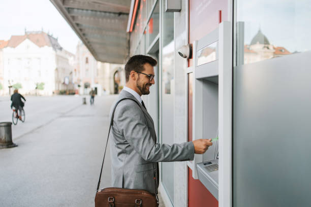 istock Businessman on city street using ATM machine 1429991387