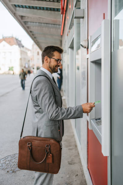 istock Businessman on city street using ATM machine 1429991400