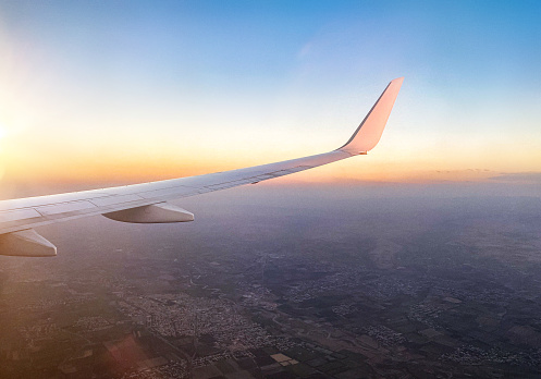 Travelling by plane. Plane wing at sunset during landing