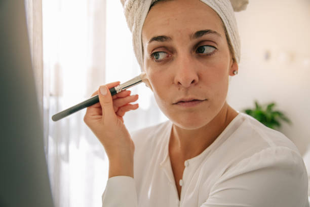 istock Beautiful woman smiling and applying makeup in apartment before going to work 1429998499
