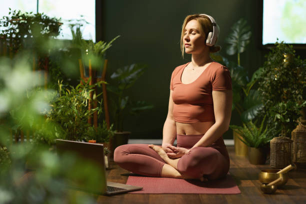 mujer moderna meditando en la casa verde moderna - relaxation exercise audio fotografías e imágenes de stock