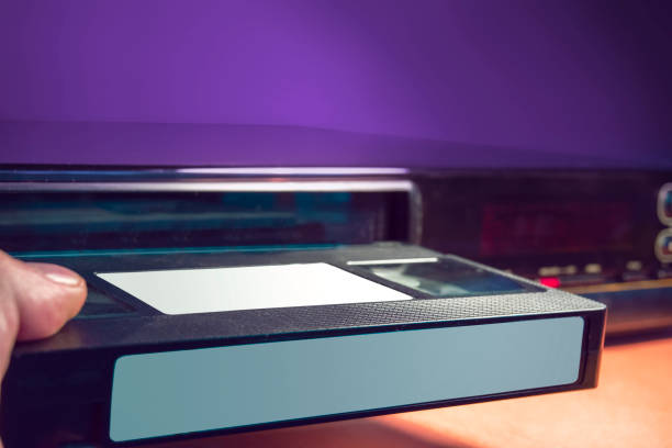 istock A hand inserting a blank VHS cassette into a vintage VHS player. 1430002433