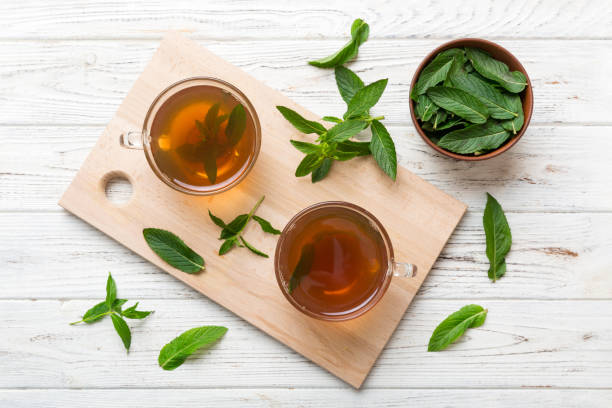 テーブルの背景にミントティーの�カップ。コピースペース付きの新鮮なミントトップビューの緑茶 - tea cup tea cup herbal medicine ストックフォトと画像