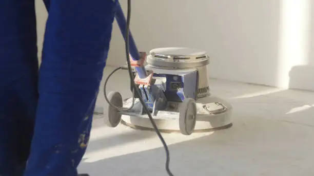 Man polishing marble floor in modern office building. Man works with grinding machine for floor.