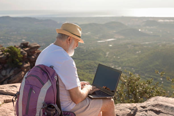 istock senior digital nomad sitting on the summit working on his laptop 1430008254