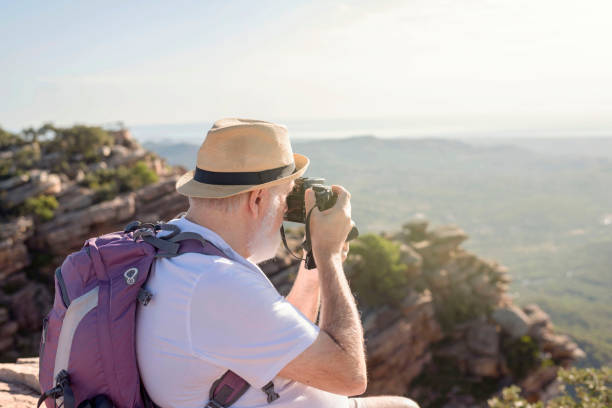 istock an older hiker sitting on the summit taking a picture 1430008279