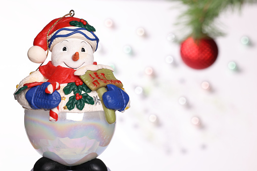 Isolated photo of a girl hand in shirt holding christmas decorative snowball toy on white background.