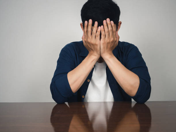 istock Sadness man sit at table,Depressed man close his face by hands 1430014992