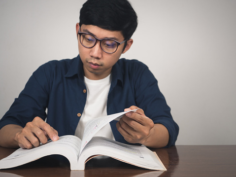 Man wear glasses open book page for learning at the table