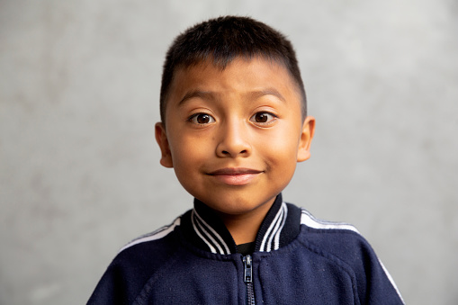Closeup shot of little boy smiling with freckles. Portrait of happy male child looking at camera isolated on white background. Happy cute boy with brown hair standing against white background.