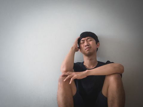 Depressed man sit at the wall thoughtful with his life