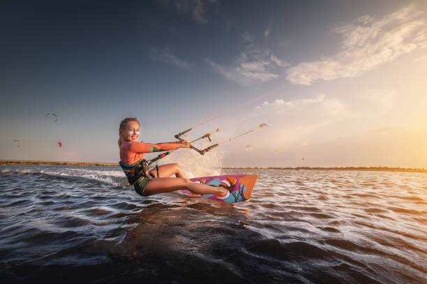 ウォータースポーツ。少女は青い海の船上で空に凧でカイトサーフィンに従事し、水しぶきで波に乗っています。レクリエーション活動、 - women sensuality surfing water sport ストックフォトと画像