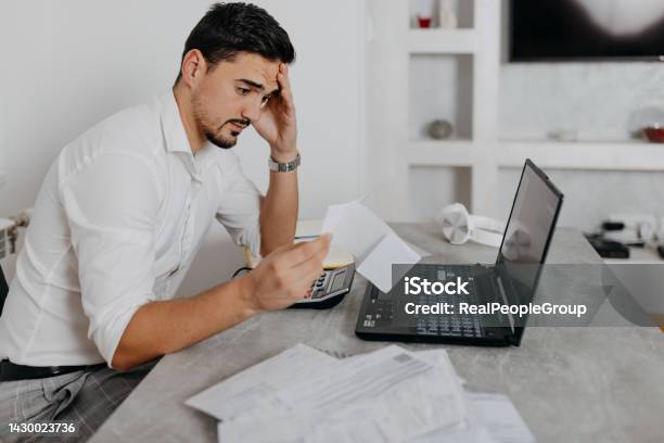 A Midadult Man Experiencig Emotional Stress Because Of The Bills Stock Photo - Download Image Now