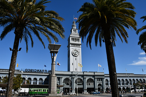San Francisco, CA, USA - October 6, 2019: The San Francisco Ferry Building, with an American flag flying at half mast.