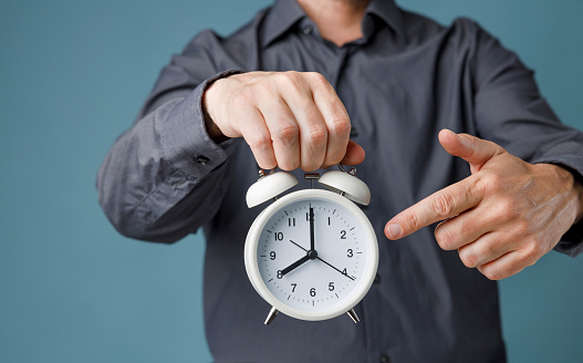 Man's finger pointing at clock times at 8 o'clock, reminder time to do something or timing notice concept