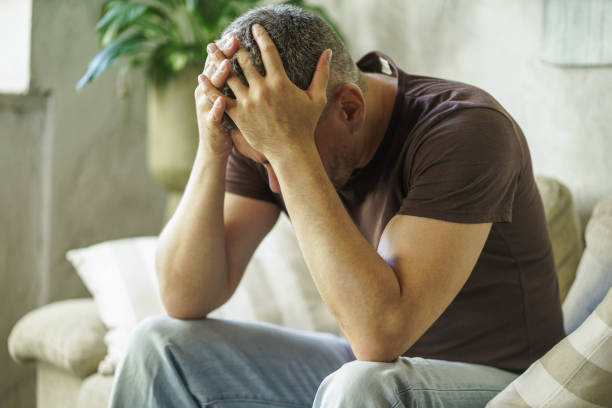 istock Male problems frustrated middle age man covered his head with hands sitting on the sofa in home interior. Lack of inspiration sad man. Male health concept. Family crisis, sad man at home 1430031791