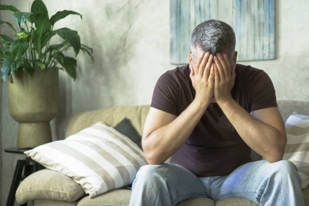 istock Exhausted middle age grey haired man covered his face with hands sitting on the sofa in home interior. Lack of inspiration sad man. Middle age man crisis concept. Family crisis, sad man at home 1430031817