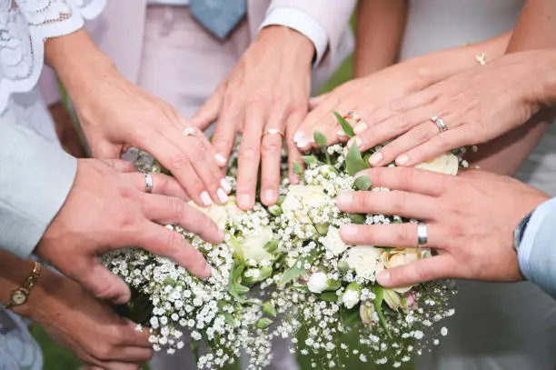 Photo of Bride and Groom hands over wedding flowers showing their marriage rings