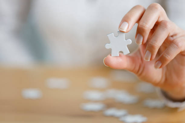istock Woman's hand showing a jigsaw puzzle piece on wooden table 1430032272