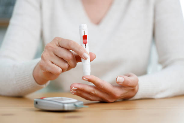 jeune femme faisant l’essai de sucre de sang à la maison - blood sugar test examining instrument of measurement diabetes photos et images de collection