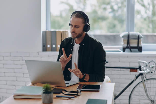 istock Confident man in headphones using laptop while having web conference from office 1430035752