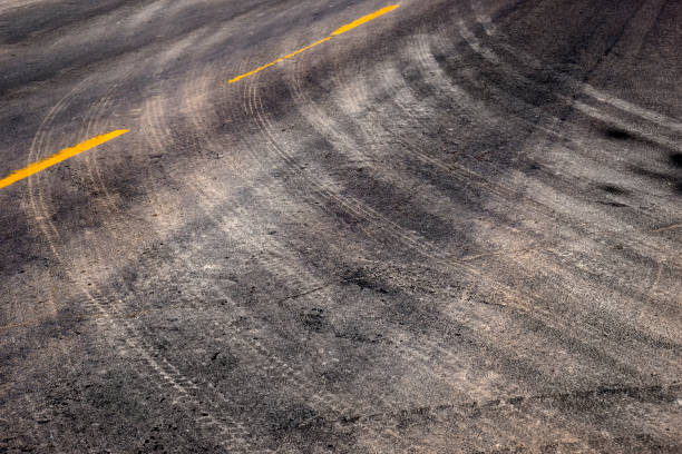 istock Tire Tracks Turning on Road with Yellow Stripe Lines 1430037945
