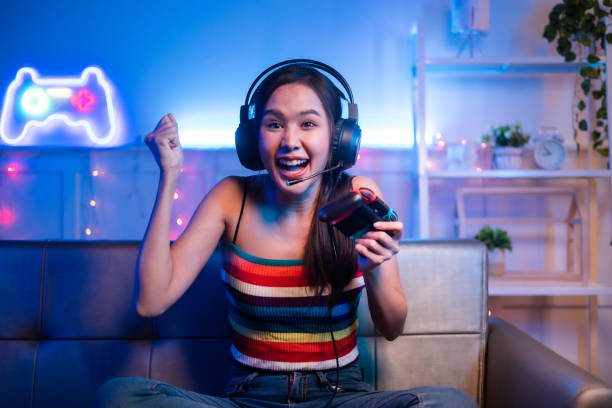 istock Young asian woman is using virtual reality headset. Neon light studio portrait. Concept of virtual reality, simulation, gaming and future technology.Asian woman play game in living room. 1430039879
