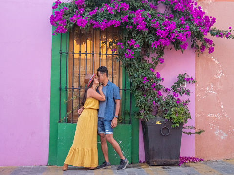 They pose in front of a door, colourful setting.