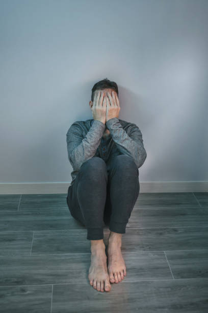 istock Man crying while covering his face with hands sitting on the floor 1430048950