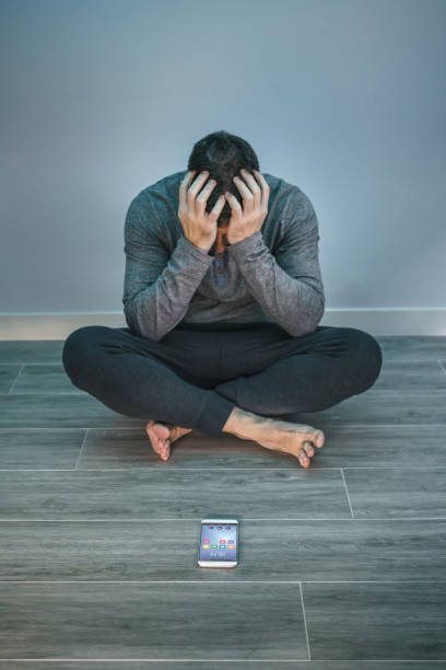 istock Man with problems sitting on the floor behind of his mobile 1430048986