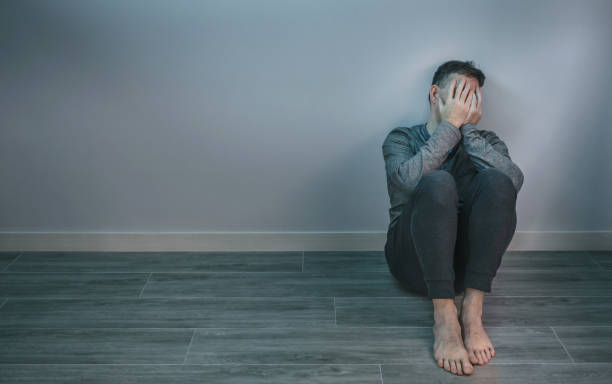 istock Man crying while covering his face with hands sitting on the floor 1430048996