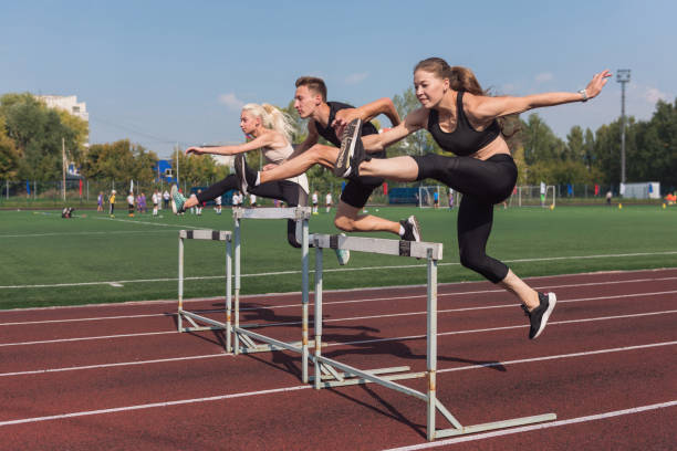 deux athlètes, une femme et un homme qui courent des haies - track and field athlete women vitality speed photos et images de collection