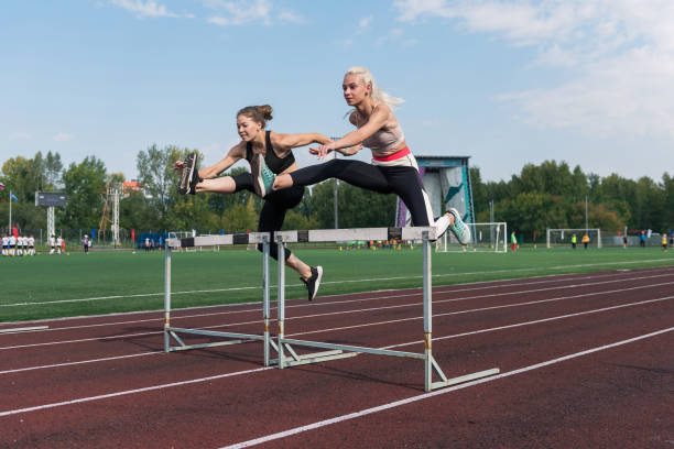 две спортсменки бегут с барьерами - hurdle sports track track and field playing field стоковые фото и изображения