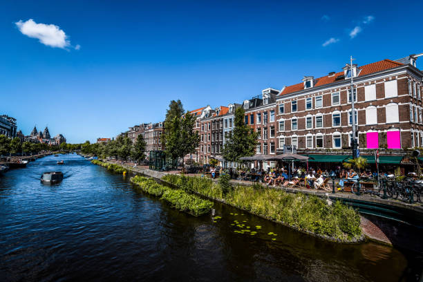 belle vue sur les cafés et les yachts qui coulent sur le canal d’amsterdam, pays-bas - montelbaan tower photos et images de collection