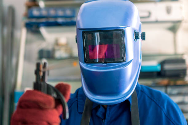 Engineering welding masks hang in a row on a wall.