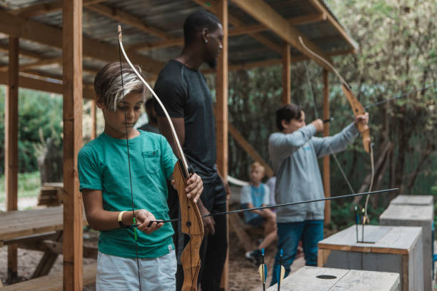 istock Male caretaker with a small group of children during an archery activity 1430055849