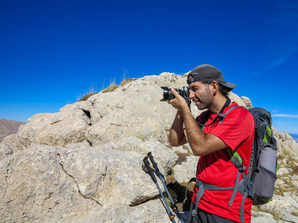 istock Man with backpack taking nature photo 1430056008