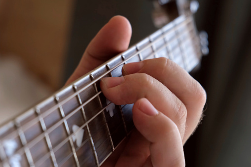 Man Playing Guitar Chord. Unrecognizable Person Rehearsing. Strumming Acoustic Guitar. Musician Plays Music. Male Fingers and Fretboard Close Up. Man Hand Playing Guitar Neck, Day light. Lesson. Learning to Play the Guitar. Closeup fingerboard