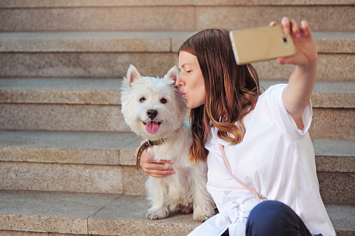 Woman making selfie picture of her kissing the dog
