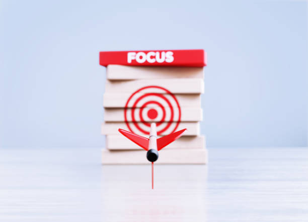 istock Arrow Hitting Red Bull's Eye Target And Focus Written Wood Blocks in Front a Defocused Background 1430076897