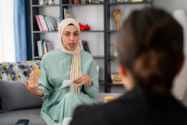paciente muçulmana feminina fazendo sessão de psicoterapia no consultório da psicóloga - middle eastern ethnicity teenage girls women sadness - fotografias e filmes do acervo
