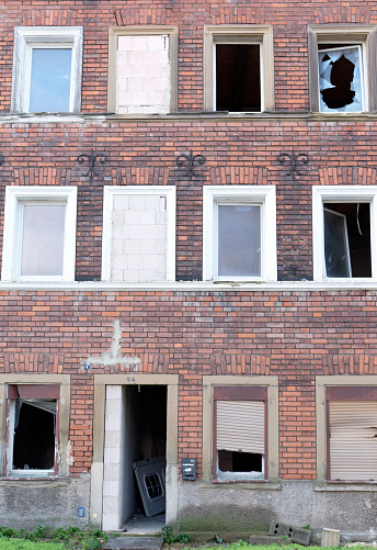 Symbolic image: Abandoned. empty, past, broken: neglected brick house facade with empty, broken windows
