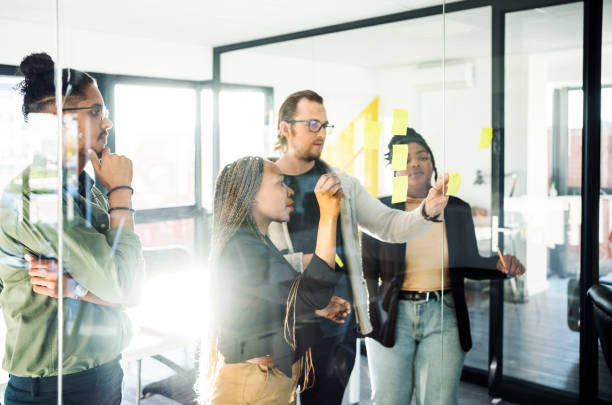 istock Business team sharing their ideas on adhesive notes to a glass wall 1430092810
