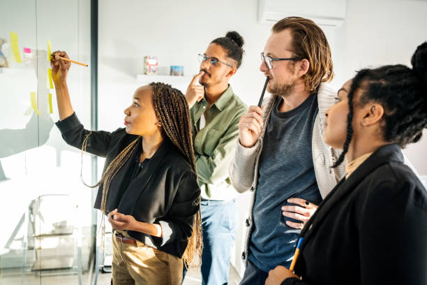 istock African woman writing on post it notes and sharing her ideas with startup team 1430092872
