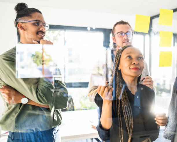 istock Businesspeople brainstorming with sticky notes on a glass wall in office 1430092898