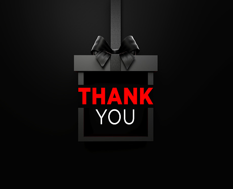 Thank You text is sitting inside of a black gift box tied with black ribbon on black background. Horizontal composition with copy space. Front view. Great use for Thank You concepts.